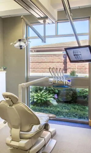 A treatment room with a large window onto the garden and a screen above the chair.